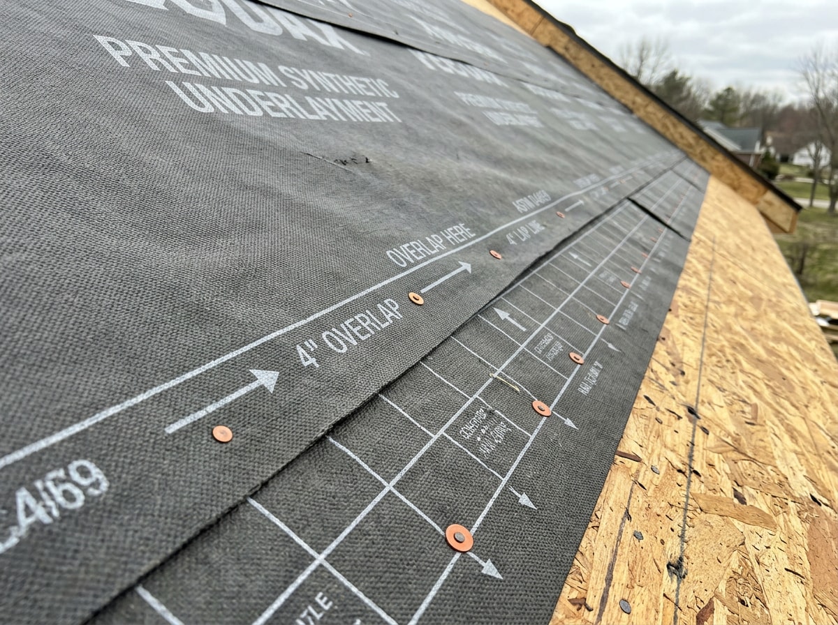 Close-up photo of synthetic roofing underlayment overlap during metal roof installation